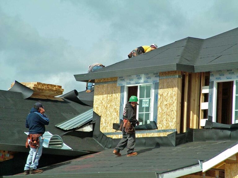 Roof valley with displaced shingles, exposed flashing, and leaves collected along the drainage channel.